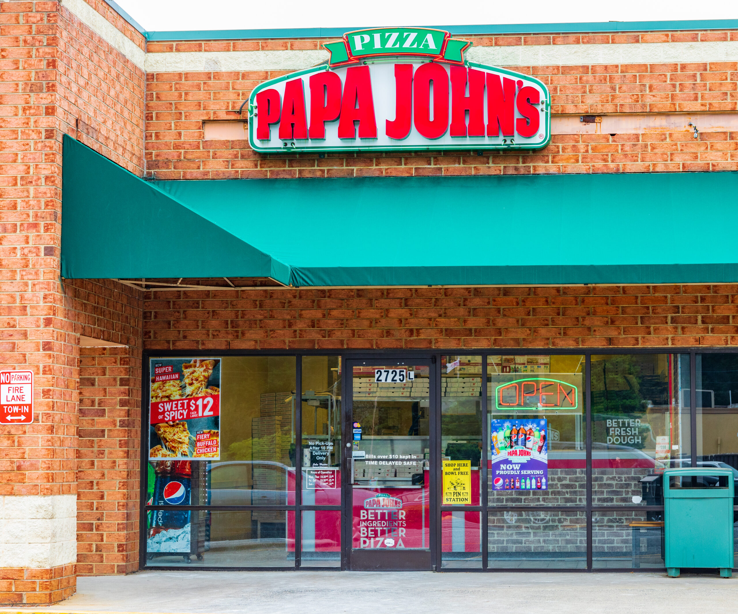 Papa John’s Pizza storefront with green awning and illuminated open sign.