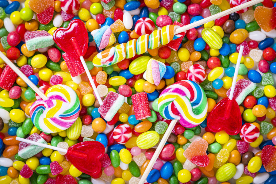 Top view of an assortment of multicolored candies, lollipops and jelly beans background. 