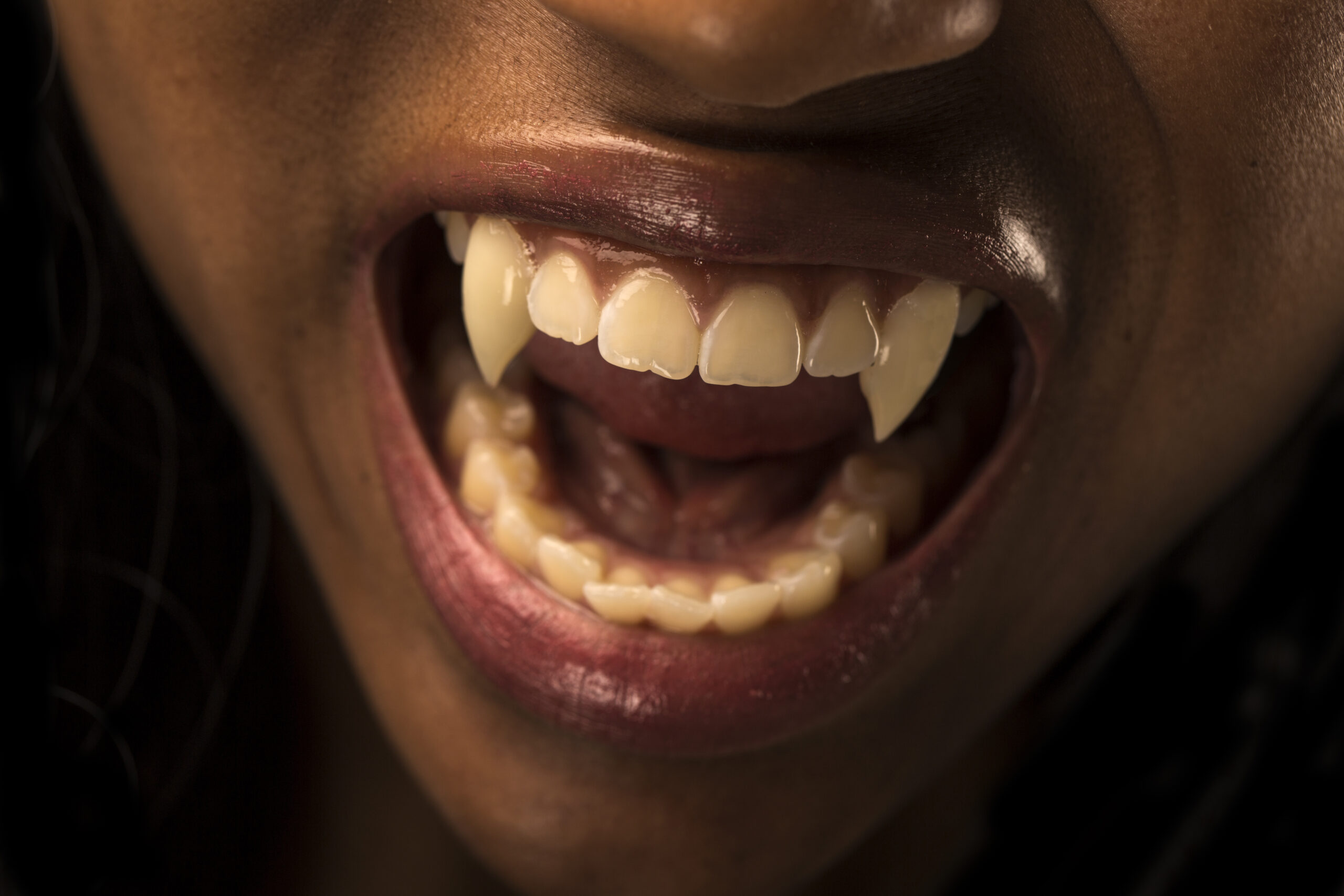 Vampire revealing fangs, horizontal composition on a dark gray background.