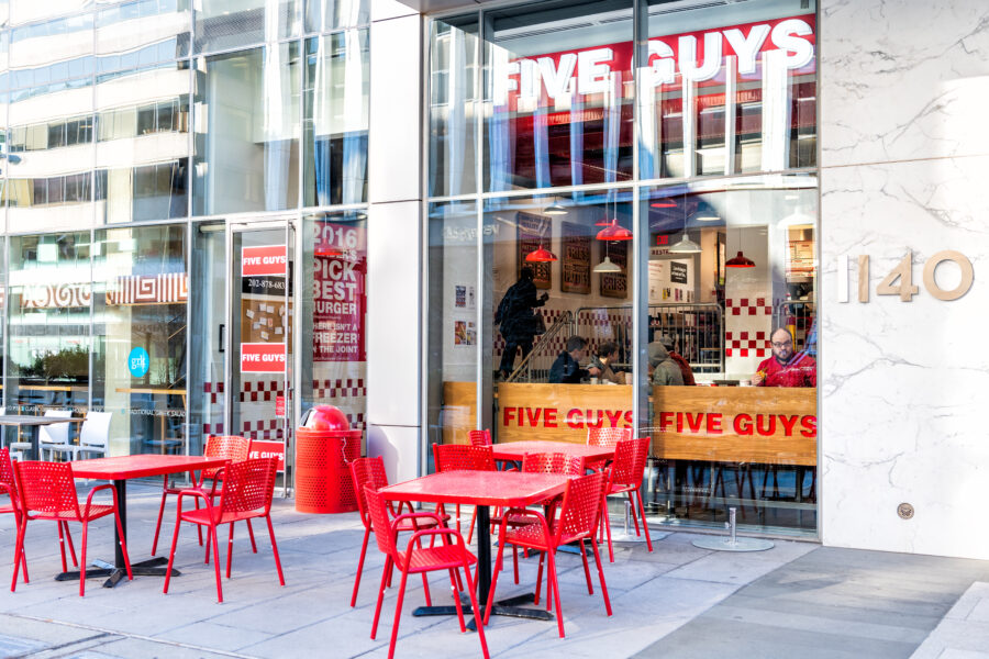 Five Guys restaurant, store burger chain entrance with chairs, tables, outside, outdoor sitting area, people inside eating