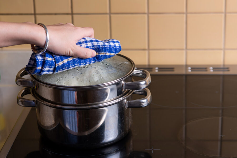 Woman preparing Chinese steamed buns baozi on the metal steamer at home