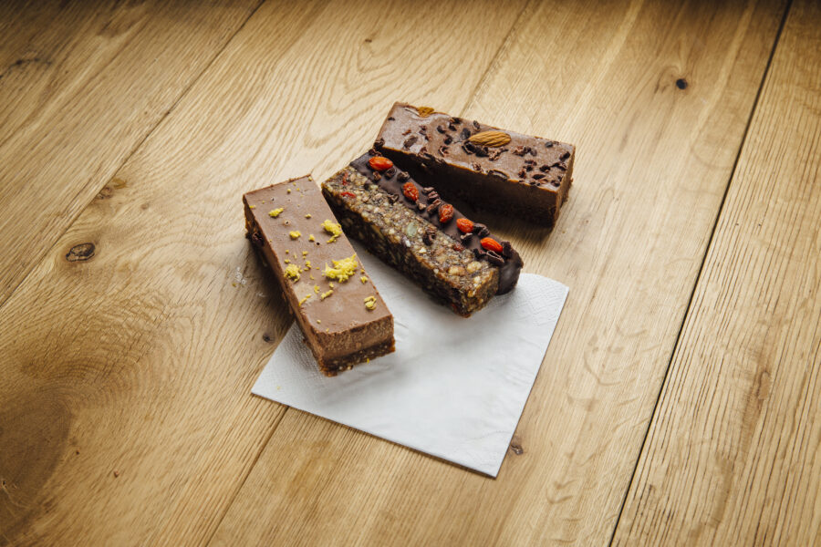 3 suprfood chocolate treats on a napkin. These are a walnut and cacao brownie, granola and seed flapjack and a lucuma and pecan bar.