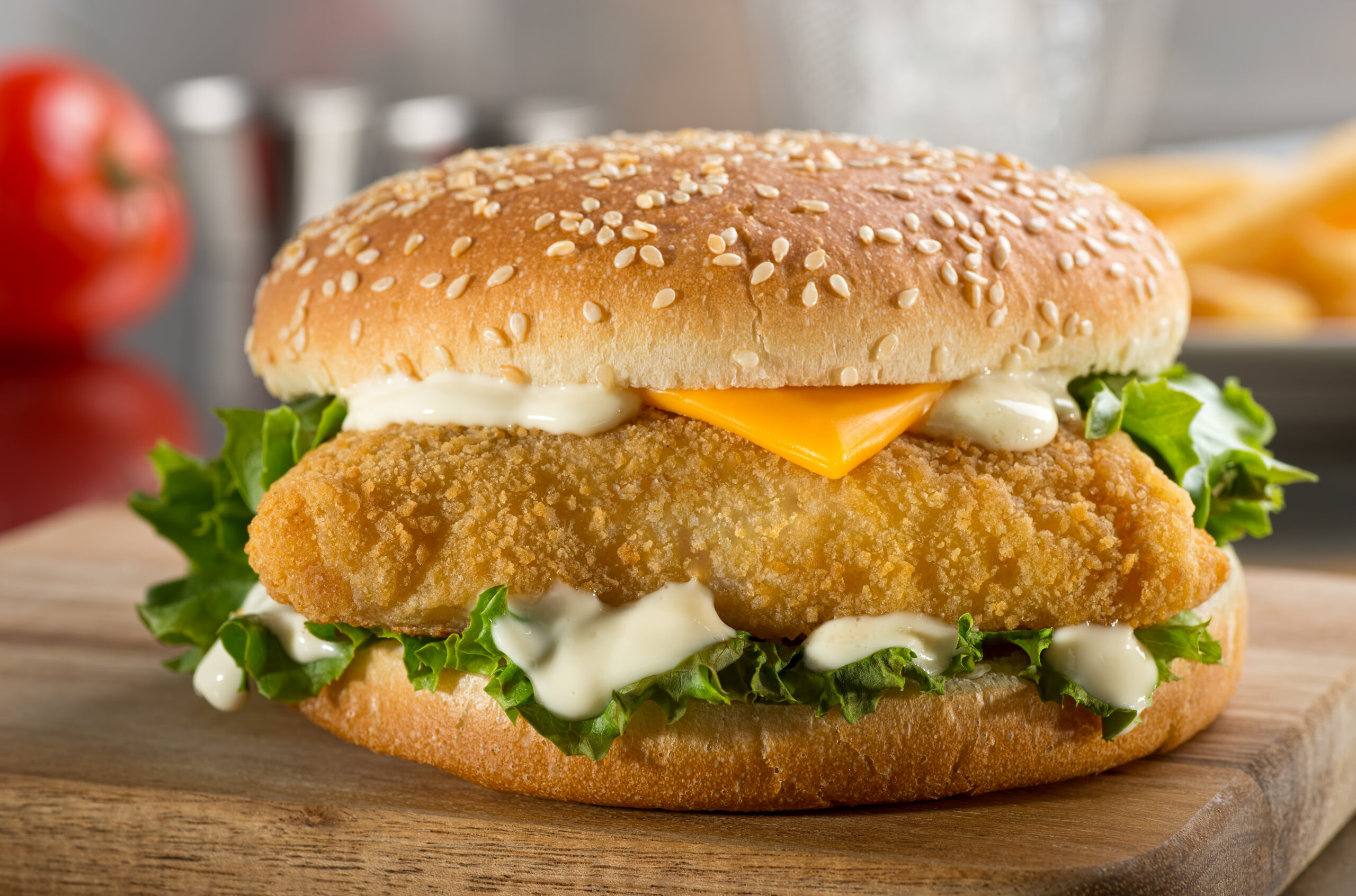 A delicious crispy fish burger with cheese, lettuce, and mayonnaise.