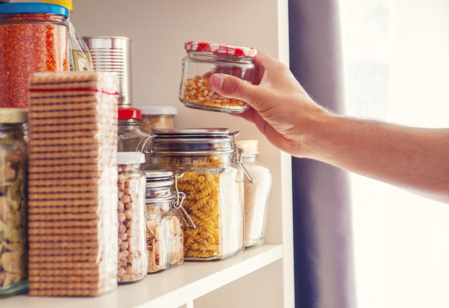 A Man Takes or Places Glass Jars Filled With Legumes From A Shelf In The Pantry