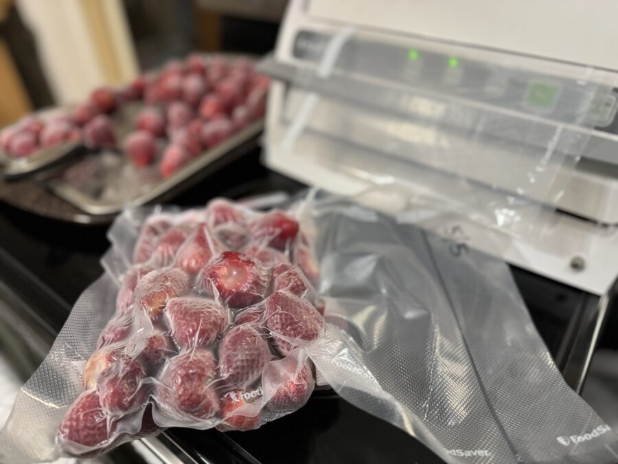 A vacuum sealed bag of fresh red strawberries lying on a kitchen counter