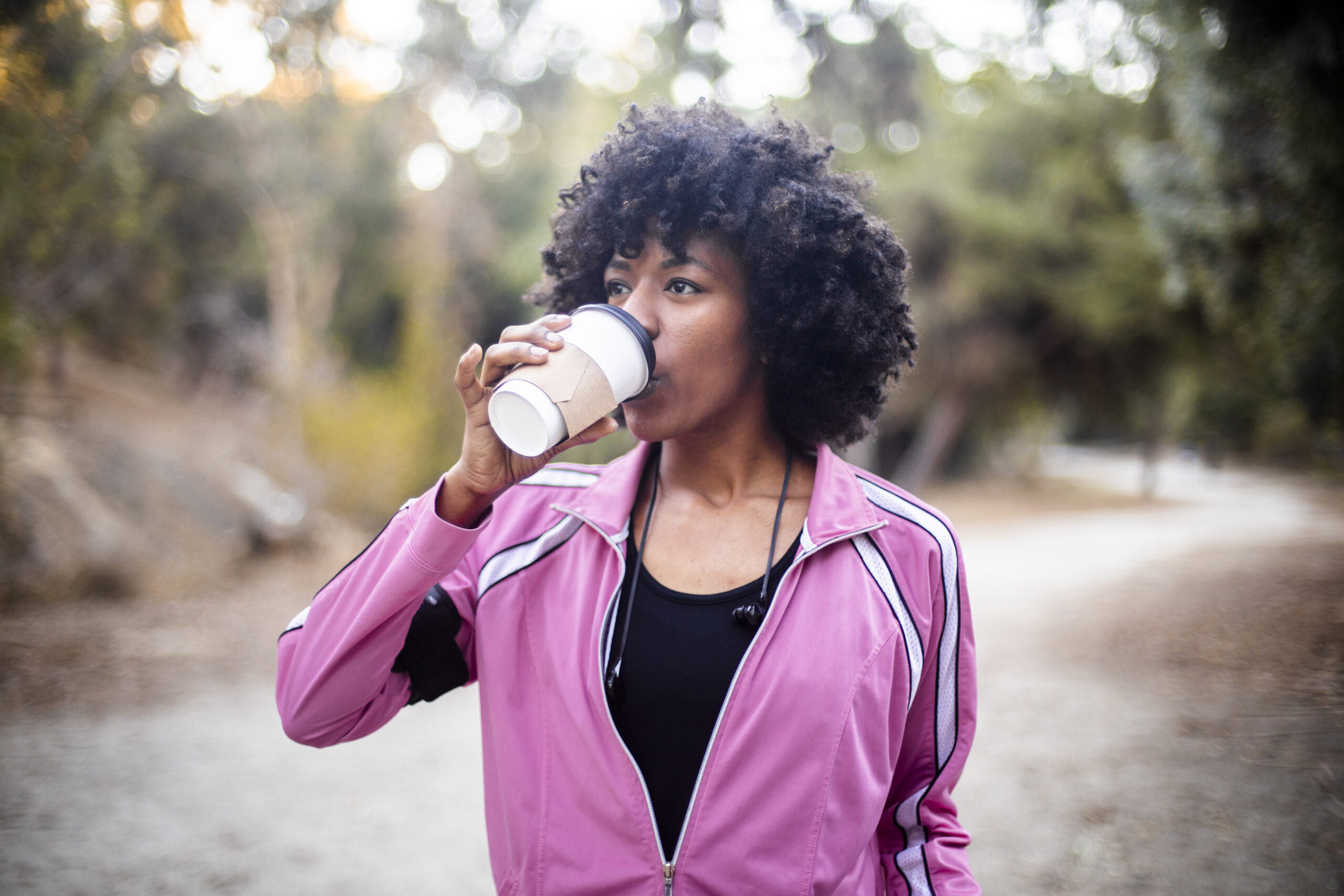 A young black woman walking with a cup of coffee