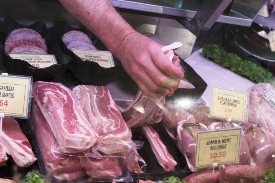 Meat behind a deli counter with hand reaching down