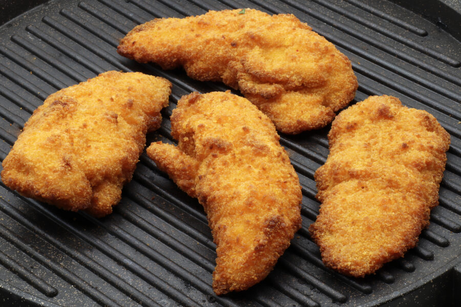 Chicken fried steaks on the cooking plate.