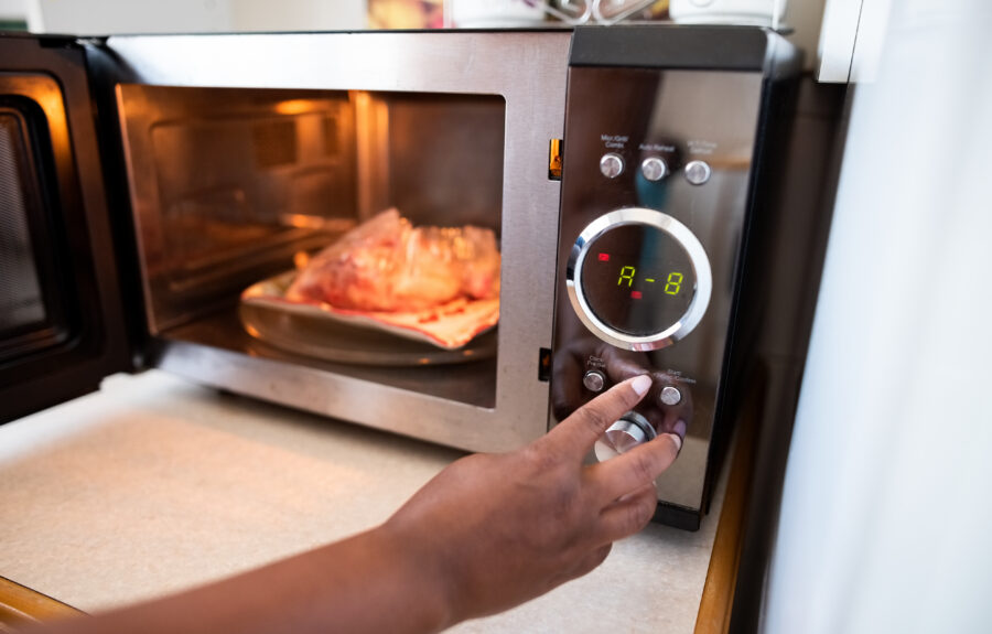 Close-up of a female hand staring the microwave oven to cook food