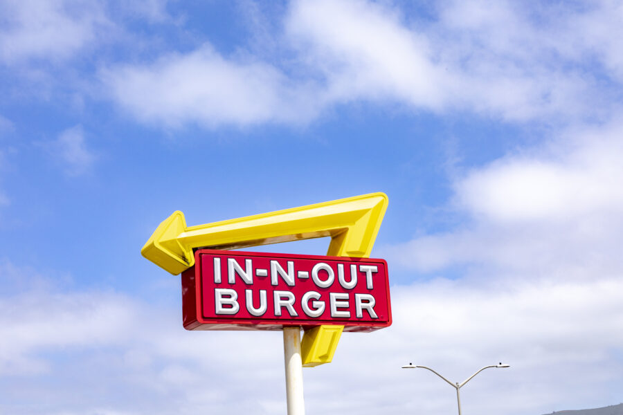 neon sign for a fast food restaurant in-n-out burger under blue sky.