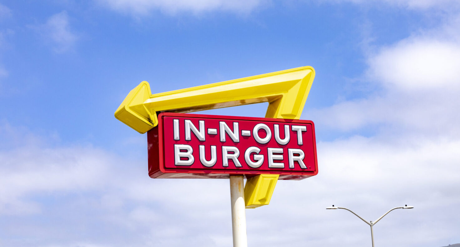 neon sign for a fast food restaurant in-n-out burger under blue sky.
