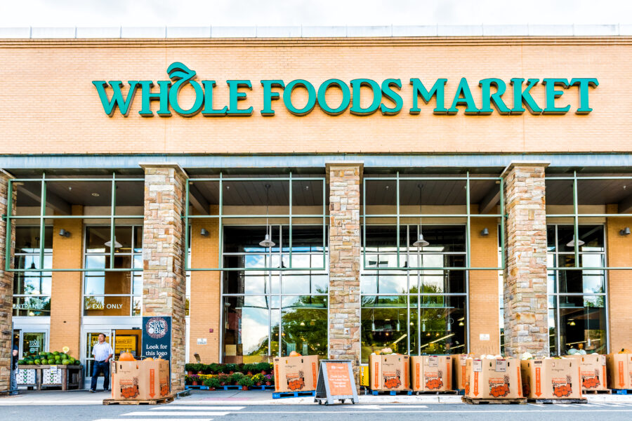 Fairfax: Green Whole Foods Market grocery store sign on exterior building in city in Virginia with people walking and autumn displays of pumpkins for Halloween