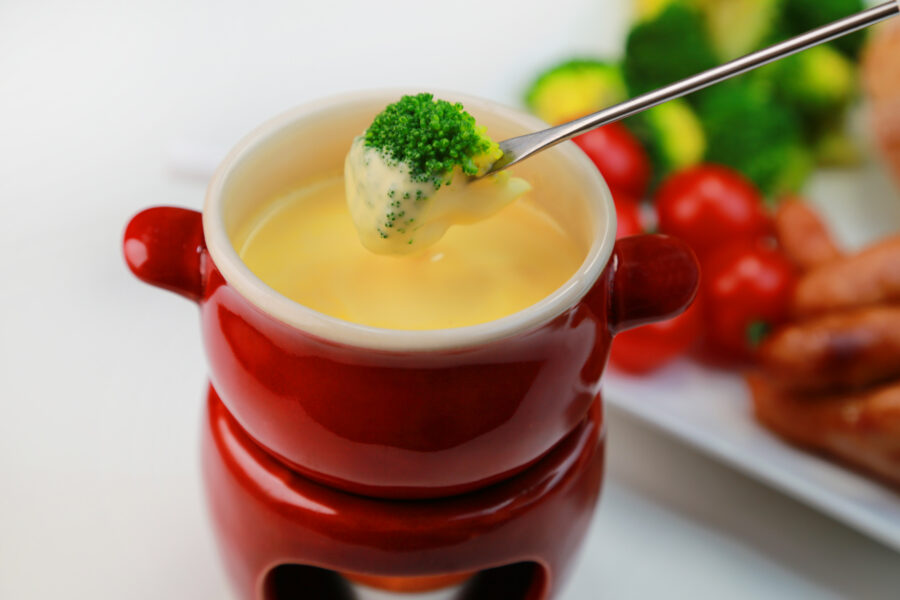 dipping broccoli into pot of cheese fondue