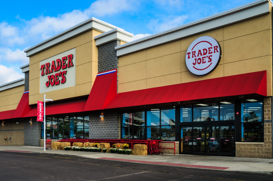 Foxboro, Massachusetts, USA - September 4, 2015: A row of red shopping carts are lined up, ready for use, behind bales of hay and potted chrysanthemums. With 457 stores, mostly in California, Trader Joe's  is a market leader in organic and fresh food groceries in the United States.  Some locations, such as this one in Foxboro, Massachusetts also have a wide wine and beer selection.