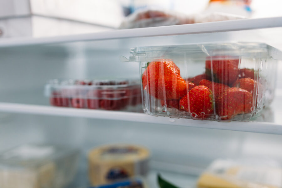 Fresh strawberries and raspberries on a fridge shelf, a close up.