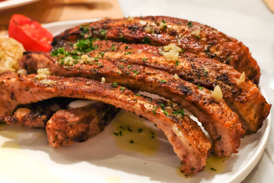 Fried pork ribs on a wooden plate decorated with salad