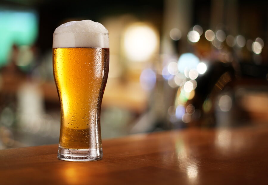 Glass of light beer on a dark pub.