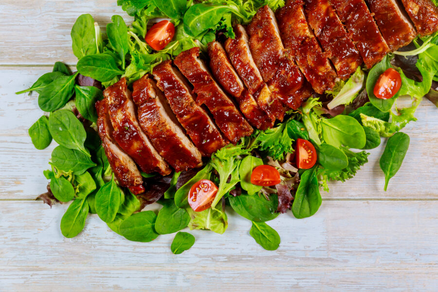 Grilled spare baby back ribs with green salad and tomato.