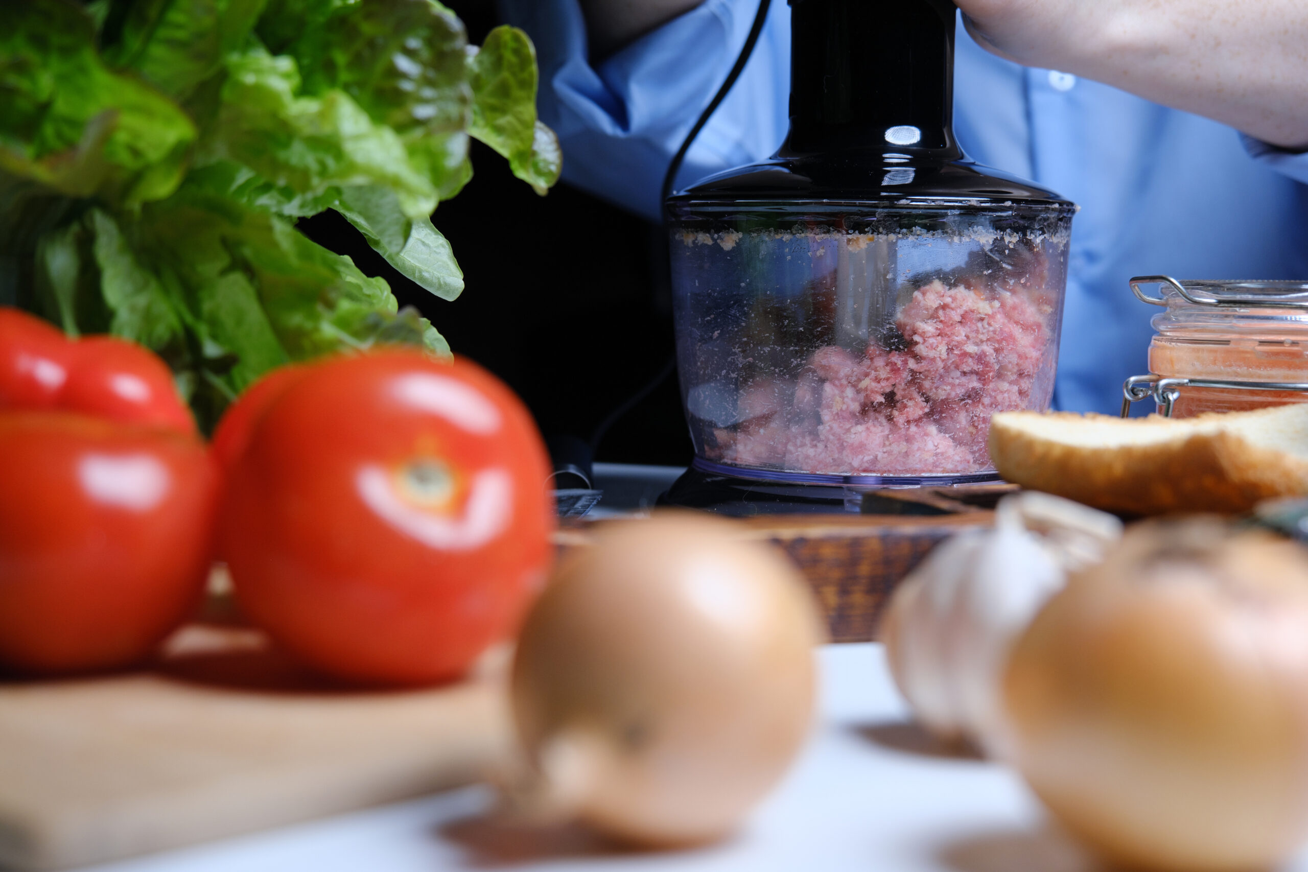 Person is mincing meat using electric food processor at home