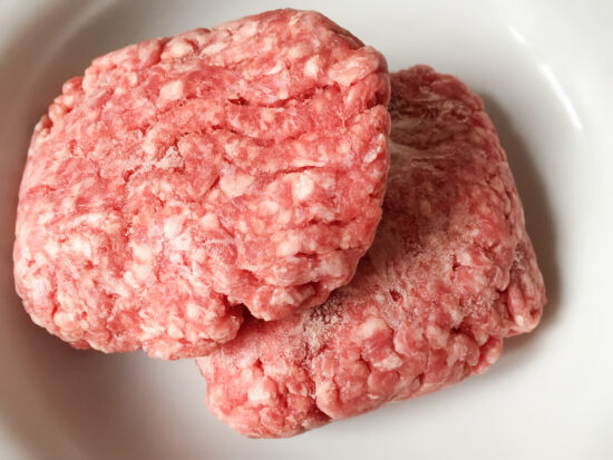Frozen minced meats in a plate. Frozen ground beef