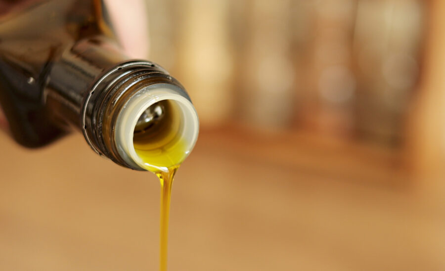 Pouring olive oil from glass bottle. 