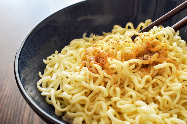 Instant noodles with seasonings on fork in a bowl. Asian food style.