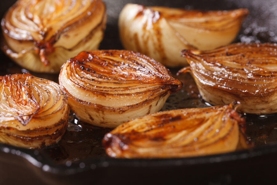 caramelized onion halves with balsamic vinegar in a pan close-up, horizontal