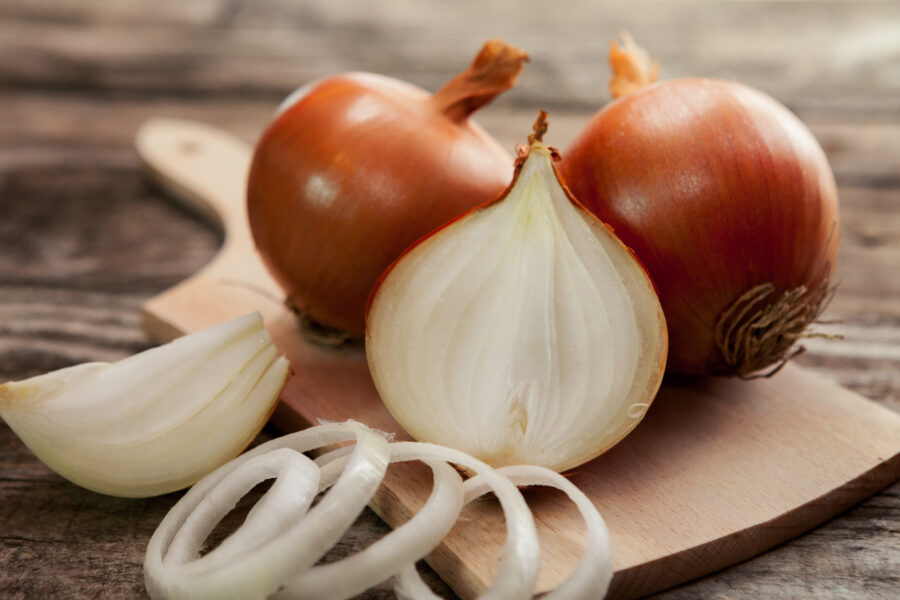 Fresh onions and one sliced onion on chopping board