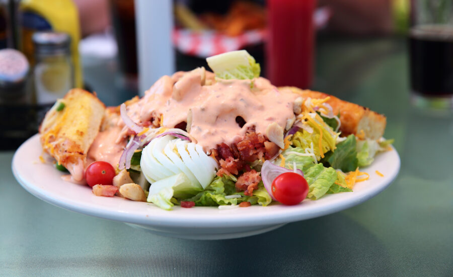 Green salad with Thousand Island dressing, bacon, egg, chicken, and cherry tomatoes