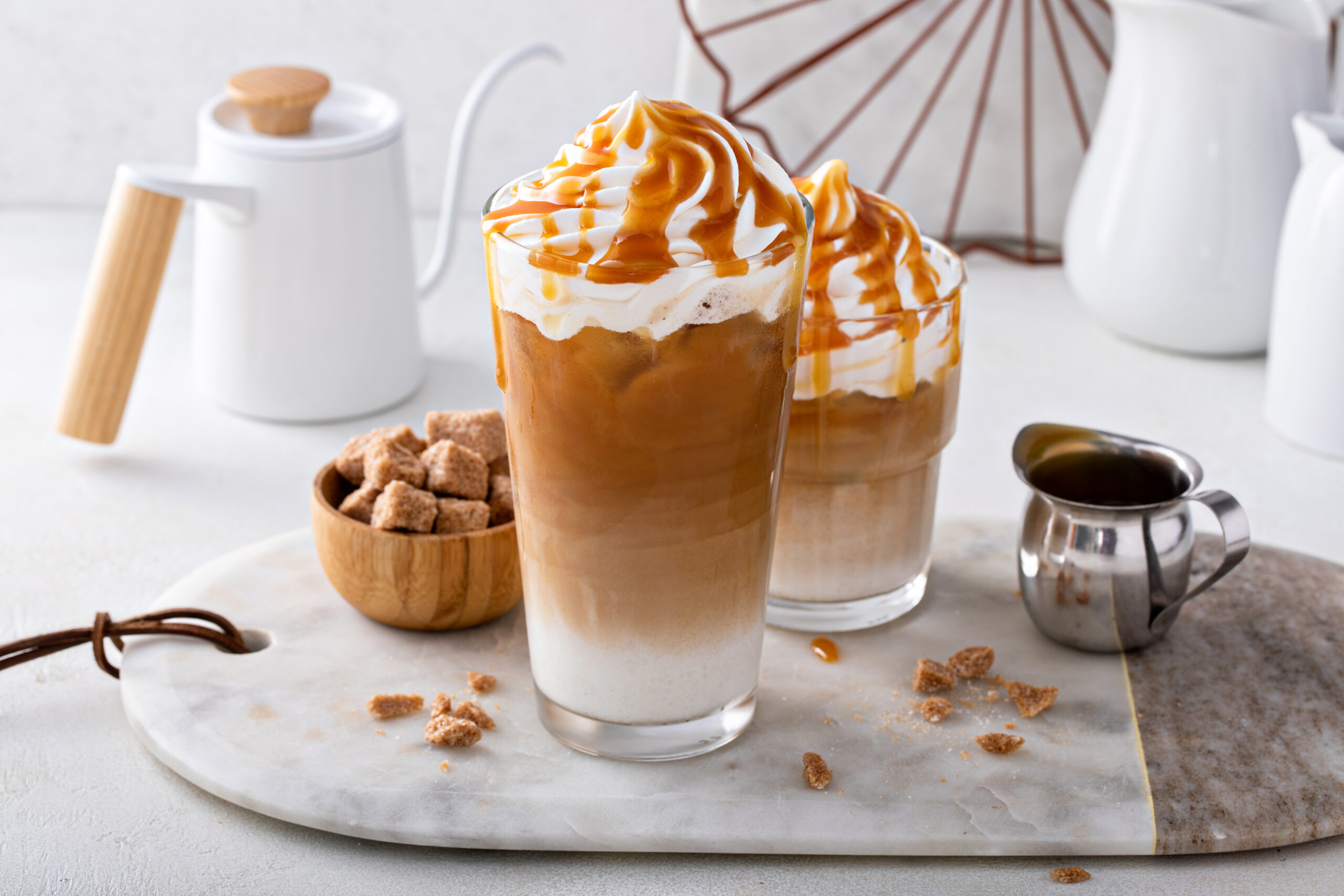 Iced caramel latte topped with whipped cream and caramel sauce, refreshing and sweet coffee drink