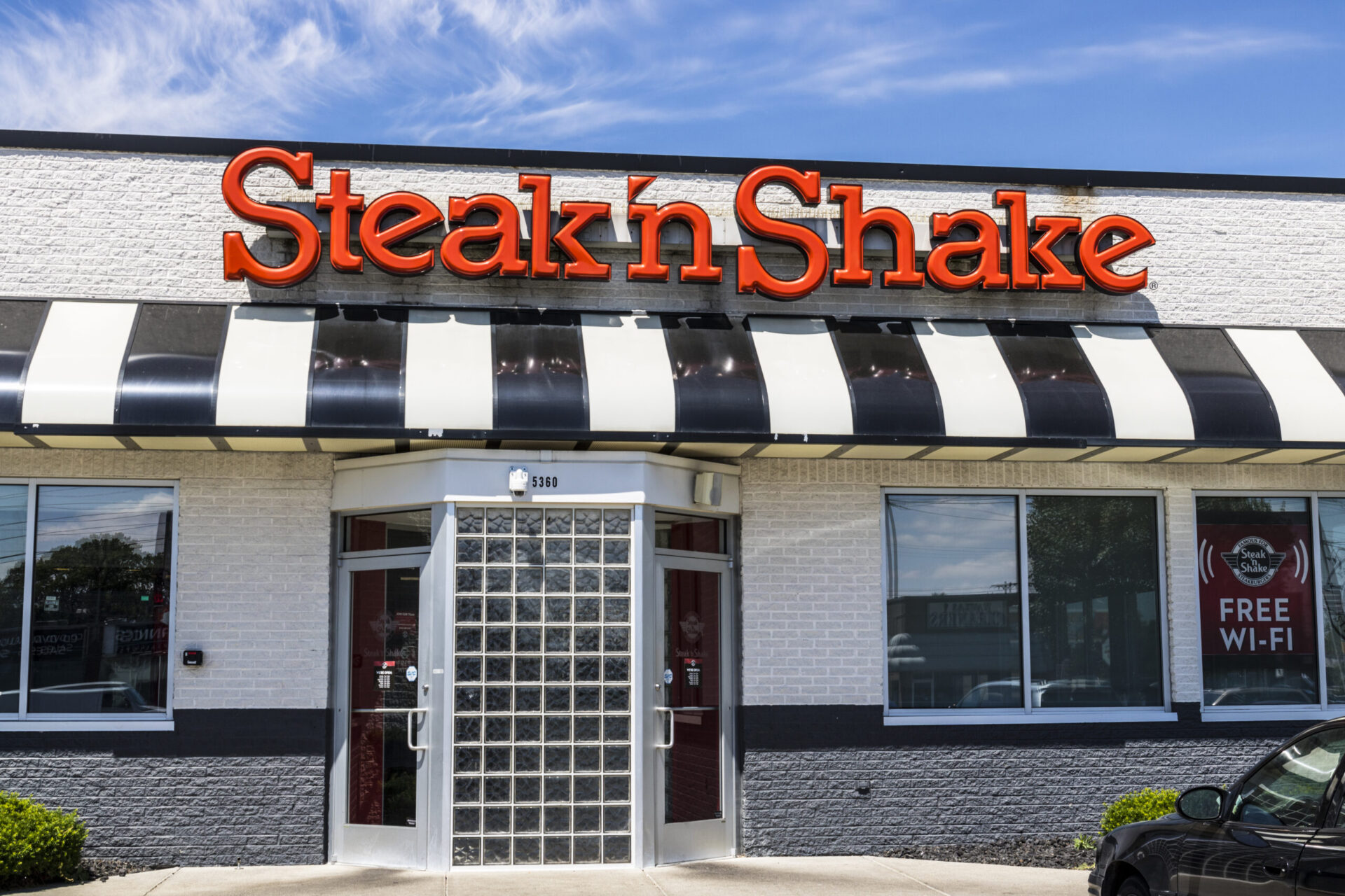 Steak ’n Shake restaurant exterior with red signage and striped awning above the entrance.