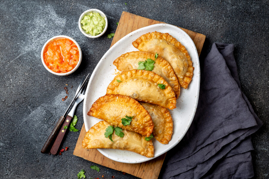 Latin American fried empanadas with tomato and avocado sauces. Top view.