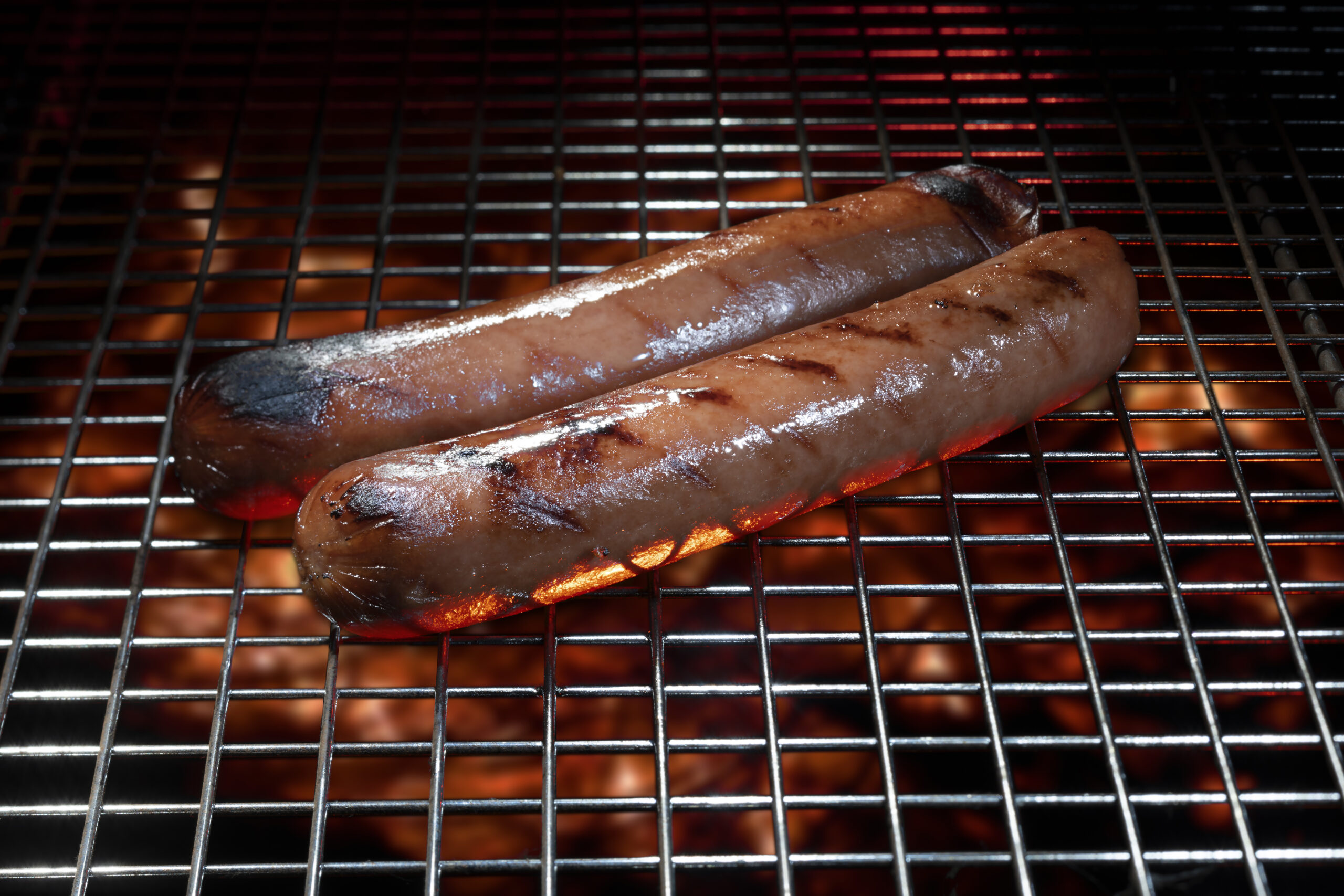 Pair of hot dogs cooking on a barbecue with copy space