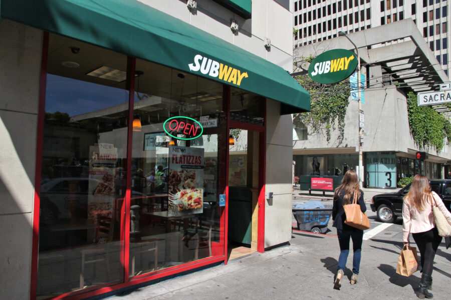 People walk by Subway sandwich store in San Francisco, California. 
