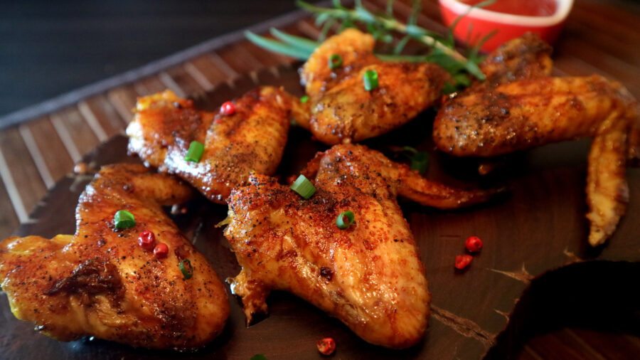 Rosted chicken wings and sauce on wooden background.