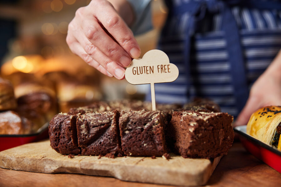 Sales Assistant In Bakery Putting Gluten Free Label Into Freshly Baked Brownies