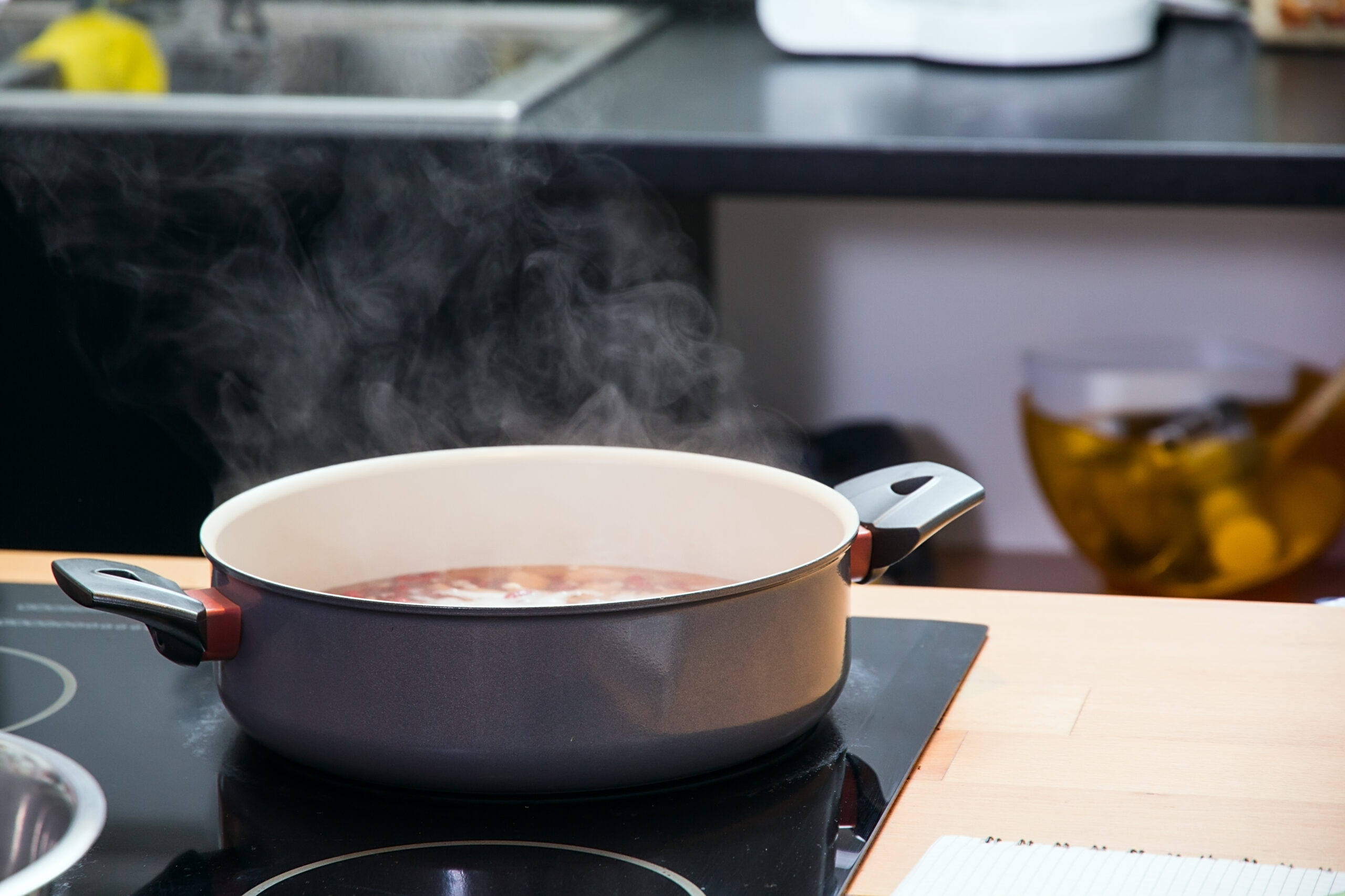 Saucepan with boiling clear soup on the plate