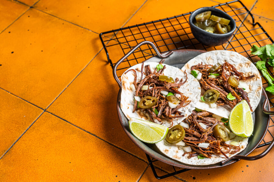 Spicy Beef Barbacoa Tacos with Cilantro and Onion. Orange background. Top view. Copy space.