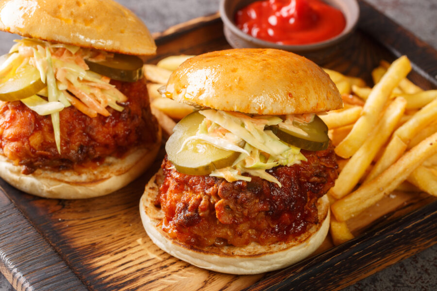 Spicy southern style fried chicken sandwich with coleslaw and pickles closeup on the tray on the table. Horizontal