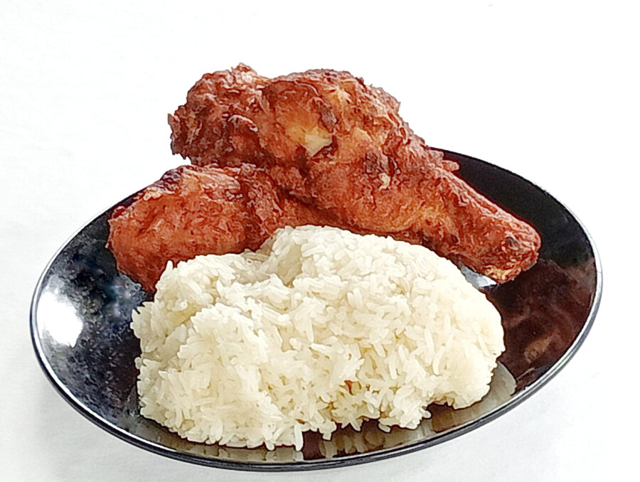 Sticky rice and Fried chicken drumsticks in a black plate on white background. Close -up shot of the food.