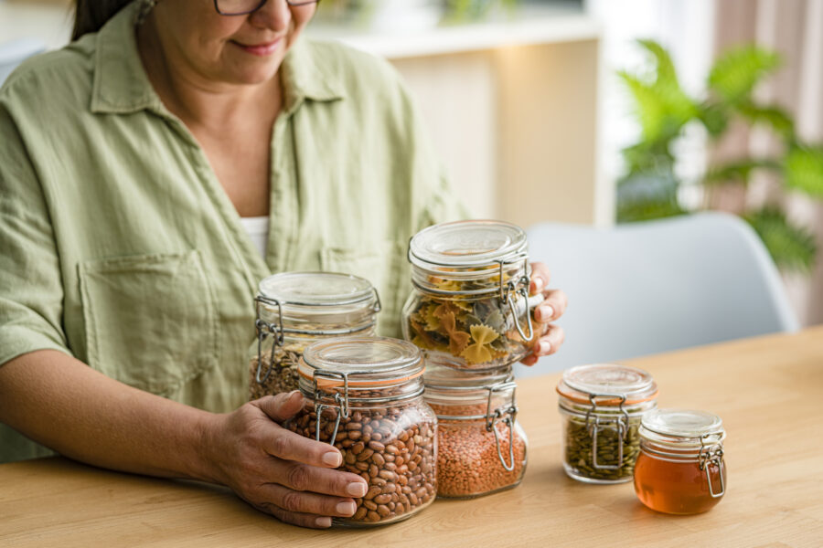 Woman using glass jars to storage dried food.