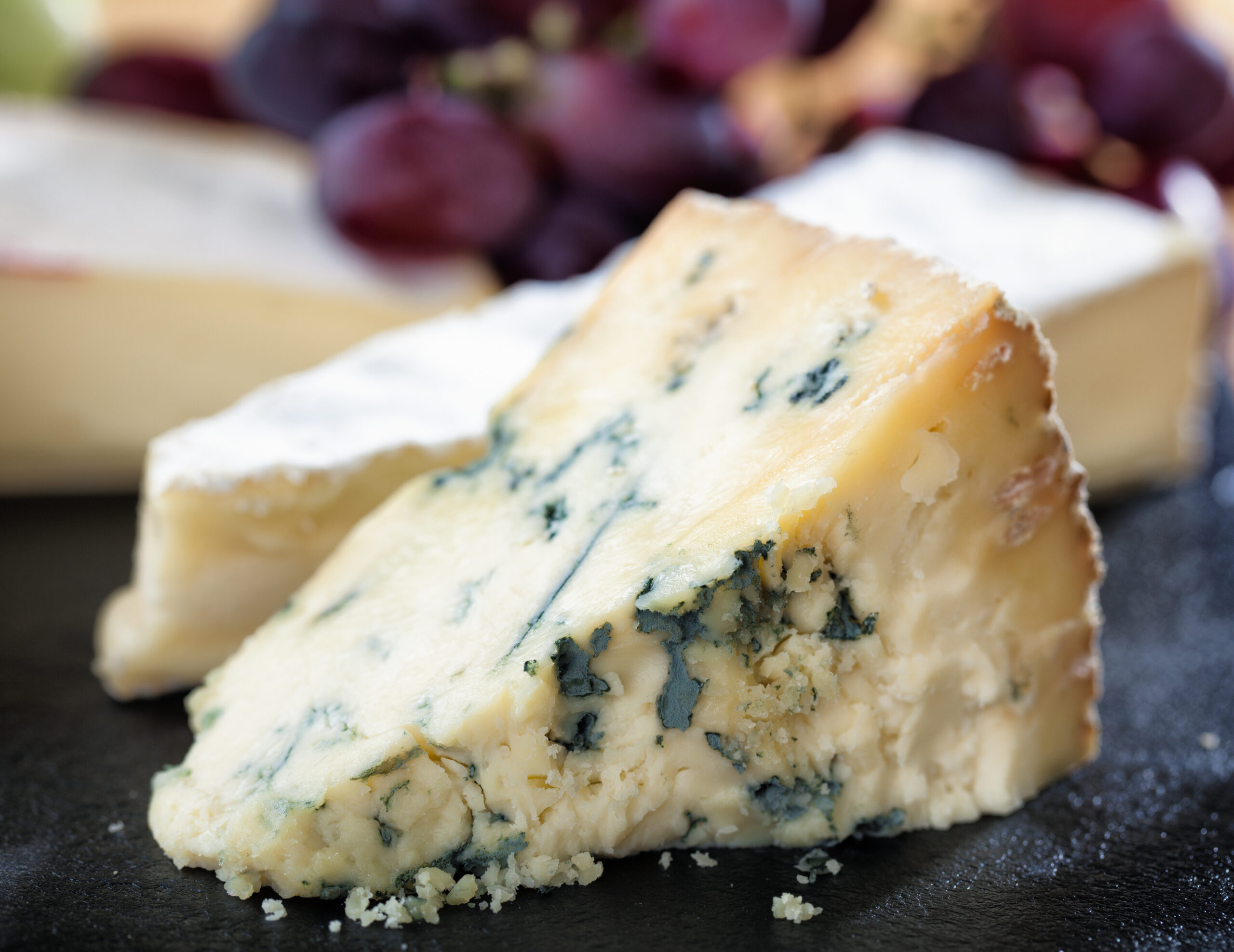 A selection of cheeses and grapes arranged on a slate cheese board.