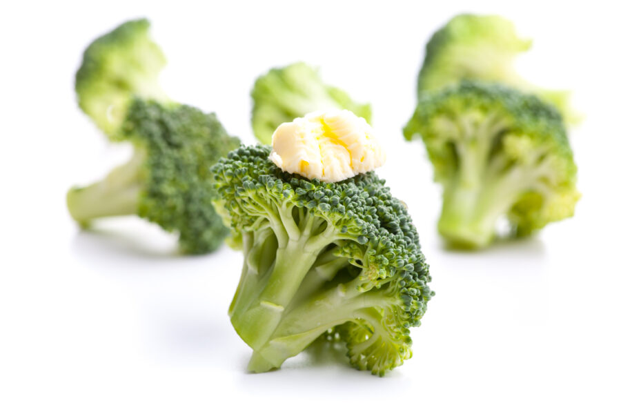 Green broccoli with butter as a garnish isolated on white background