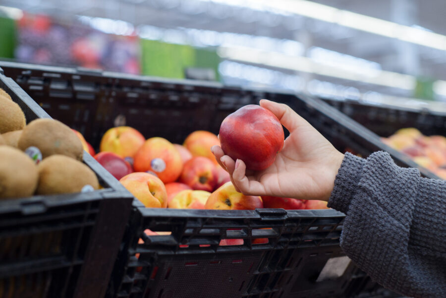 Hand holding a nectarine in a supermarket.