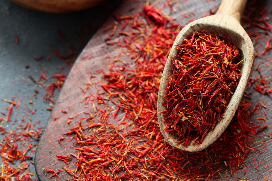 Heap of dried saffron spice in spoon on rustic background, spices and herbs concept 