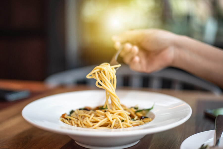 Die Hand schöpft die Spaghetti mit einer Gabel