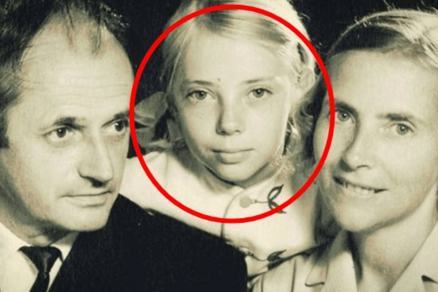 A vintage black-and-white portrait of a family with a man on the left, a woman on the right, and a young blonde girl in the center who is circled in red, drawing focus to her face.