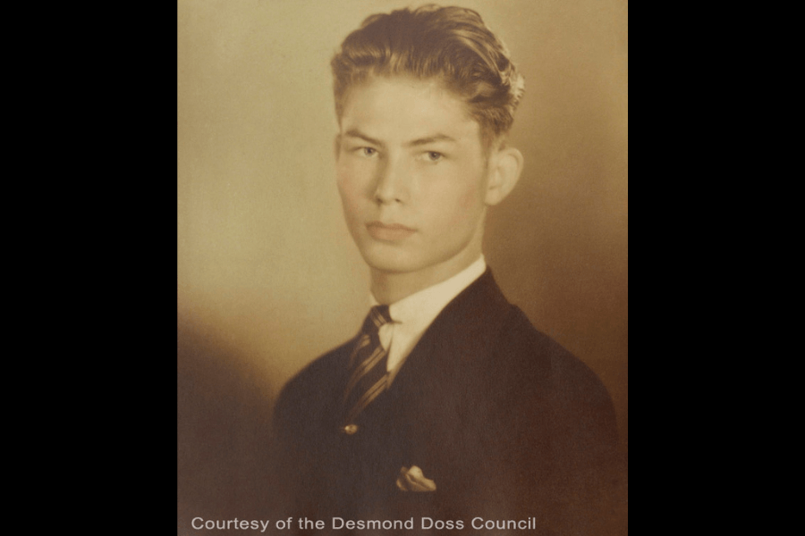 Sepia-toned portrait of a young man with neatly combed hair wearing a dark suit, striped tie, and a white pocket square. He gazes slightly to the side with a composed expression. Text at the bottom reads, "Courtesy of the Desmond Doss Council."