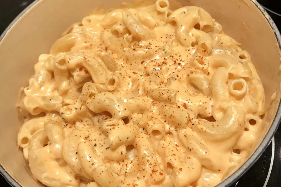 Creamy stovetop macaroni and cheese in a pot, made with elbow macaroni coated in a rich cheese sauce and lightly dusted with black pepper and paprika for extra flavor.
