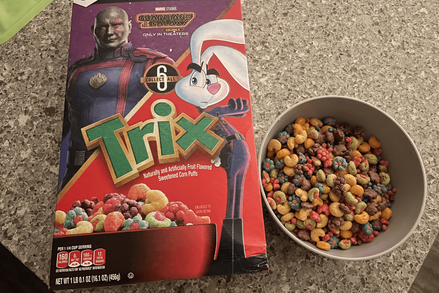 A box of Trix cereal featuring a Guardians of the Galaxy promotional design, with the Trix Rabbit and a character from the movie on the front. Next to the box is a bowl filled with colorful Trix corn puffs in various shapes and colors.